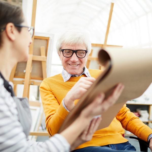 Portrait of senior art teacher working with student and smiling happily during sketch session, copy space