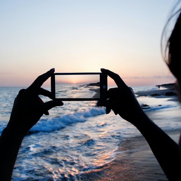 Girl is taking a sunset photo on the phone